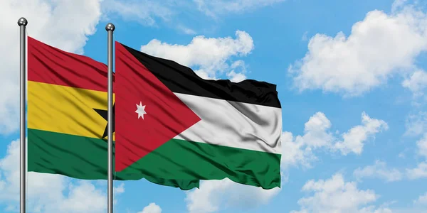 Bandera de Ghana y Jordania ondeando en el viento contra el cielo azul nublado blanco juntos. Concepto diplomático, relaciones internacionales . — Foto de Stock