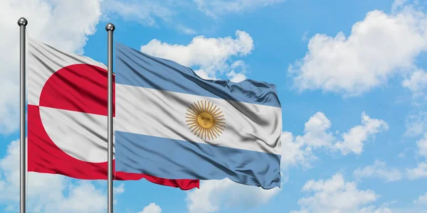 Bandera de Groenlandia y Argentina ondeando en el viento contra el cielo azul nublado blanco juntos. Concepto diplomático, relaciones internacionales . — Foto de Stock