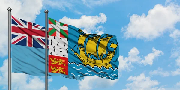 Fiji och Saint Pierre och Miquelon flagga vinka i vinden mot vit grumlig blå himmel tillsammans. Diplomatisk koncept, internationella relationer. — Stockfoto