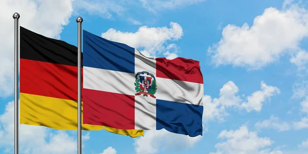 Bandera de Alemania y República Dominicana ondeando en el viento contra el cielo azul nublado blanco juntos. Concepto diplomático, relaciones internacionales . — Foto de Stock