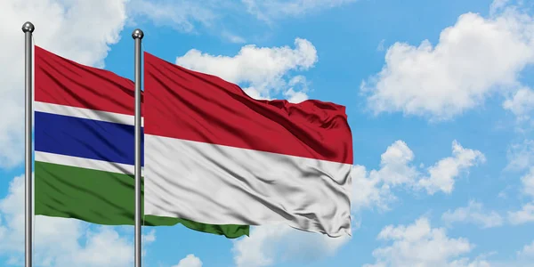 Gambia e Indonesia sventolano bandiera nel vento contro bianco cielo blu nuvoloso insieme. Concetto di diplomazia, relazioni internazionali . — Foto Stock