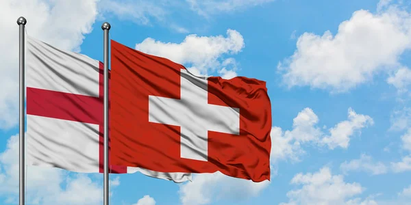 Англія і Швейцарія прапор розмахуючи в вітру проти білого хмарного синього неба разом. Концепція дипломатії, міжнародні відносини. — стокове фото