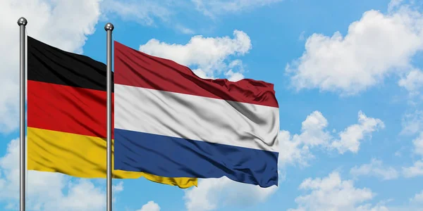 Germania e Paesi Bassi bandiera sventolando nel vento contro bianco cielo blu nuvoloso insieme. Concetto di diplomazia, relazioni internazionali . — Foto Stock