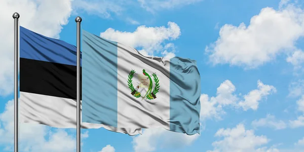 Estonya ve Guatemala bayrağı birlikte beyaz bulutlu mavi gökyüzüne karşı rüzgarda sallayarak. Diplomasi kavramı, uluslararası ilişkiler. — Stok fotoğraf