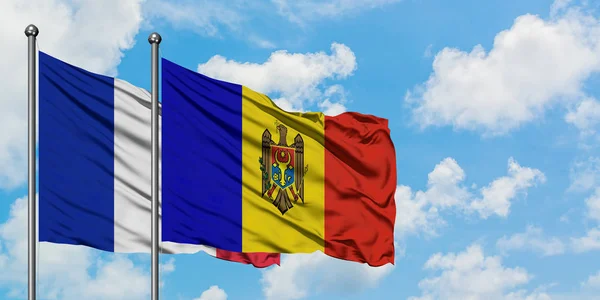 Frankreich und Moldawien wehen gemeinsam im Wind vor dem wolkenverhangenen blauen Himmel. Diplomatie-Konzept, internationale Beziehungen. — Stockfoto