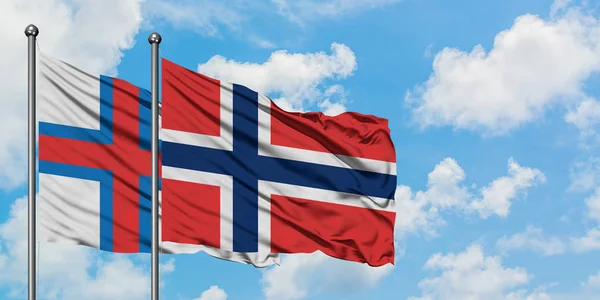 Bandera de las Islas Feroe y Noruega ondeando en el viento contra el cielo azul nublado blanco juntos. Concepto diplomático, relaciones internacionales . —  Fotos de Stock