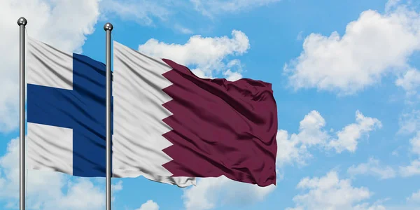 Finland och Qatar sjunker vifta i vinden mot vit grumlig blå himmel tillsammans. Diplomatisk koncept, internationella relationer. — Stockfoto