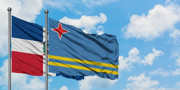 Bandera de República Dominicana y Aruba ondeando en el viento contra el cielo azul nublado blanco juntos. Concepto diplomático, relaciones internacionales . — Foto de Stock