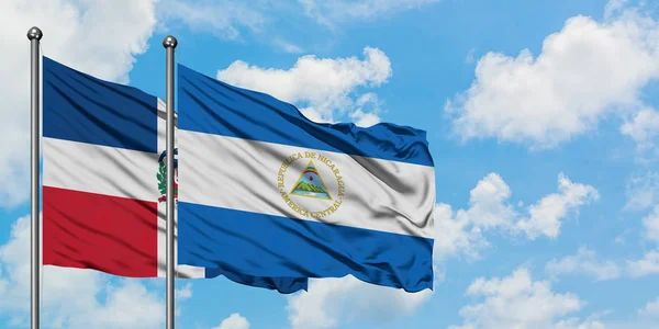 Dominicaanse Republiek en Nicaragua vlag zwaaien in de wind tegen witte bewolkte blauwe hemel samen. Diplomatie concept, internationale betrekkingen. — Stockfoto