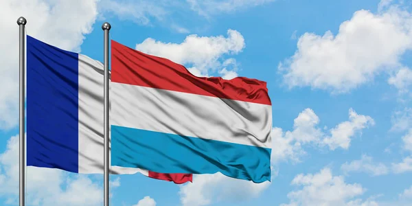 Francja i Luksemburg flaga machając w wiatr przed białym zachmurzone błękitne niebo razem. Koncepcja dyplomacji, stosunki międzynarodowe. — Zdjęcie stockowe
