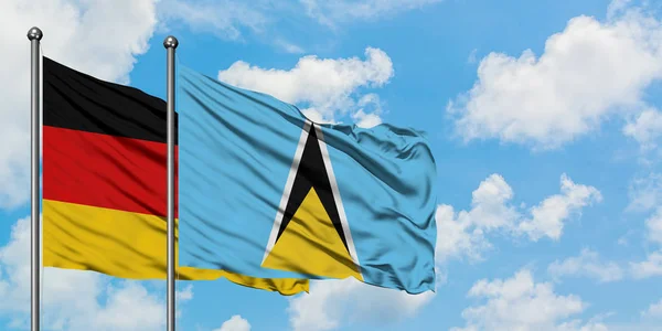 Tyskland och Saint Lucia flagga vifta i vinden mot vit grumlig blå himmel tillsammans. Diplomatisk koncept, internationella relationer. — Stockfoto