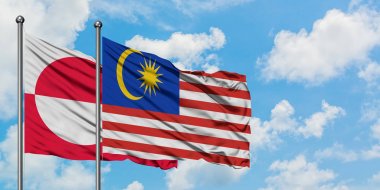 Grönland ve Malezya bayrağı birlikte beyaz bulutlu mavi gökyüzüne karşı rüzgarda sallayarak. Diplomasi kavramı, uluslararası ilişkiler.