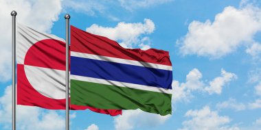 Grönland ve Gambiya bayrağı birlikte beyaz bulutlu mavi gökyüzüne karşı rüzgarda sallayarak. Diplomasi kavramı, uluslararası ilişkiler.