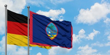 Almanya ve Guam bayrağı birlikte beyaz bulutlu mavi gökyüzüne karşı rüzgarda sallayarak. Diplomasi kavramı, uluslararası ilişkiler.