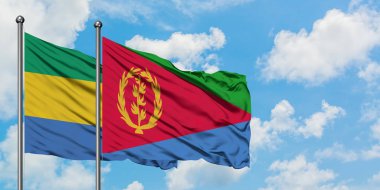Gabon ve Eritre bayrağı birlikte beyaz bulutlu mavi gökyüzüne karşı rüzgarda sallayarak. Diplomasi kavramı, uluslararası ilişkiler.