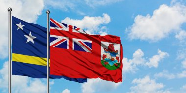 Curacao ve Bermuda bayrağı birlikte beyaz bulutlu mavi gökyüzüne karşı rüzgarda sallayarak. Diplomasi kavramı, uluslararası ilişkiler.