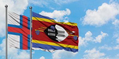 Faroe Adaları ve Svaziland bayrağı birlikte beyaz bulutlu mavi gökyüzüne karşı rüzgarda sallayarak. Diplomasi kavramı, uluslararası ilişkiler.