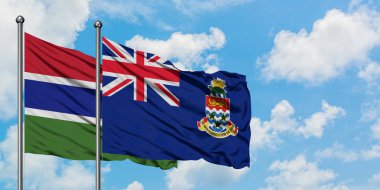 Gambiya ve Cayman Adaları bayrağı birlikte beyaz bulutlu mavi gökyüzüne karşı rüzgarda sallayarak. Diplomasi kavramı, uluslararası ilişkiler.