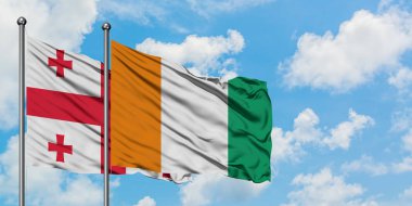 Gürcistan ve Fildişi Sahili bayrağı birlikte beyaz bulutlu mavi gökyüzüne karşı rüzgarda sallayarak. Diplomasi kavramı, uluslararası ilişkiler.