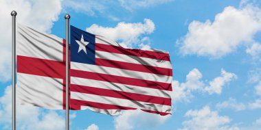 İngiltere ve Liberya bayrağı birlikte beyaz bulutlu mavi gökyüzüne karşı rüzgarda sallayarak. Diplomasi kavramı, uluslararası ilişkiler.