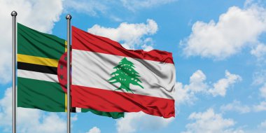 Dominika ve Lübnan bayrağı birlikte beyaz bulutlu mavi gökyüzüne karşı rüzgarda sallayarak. Diplomasi kavramı, uluslararası ilişkiler.