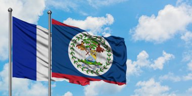 Fransa ve Belize bayrağı birlikte beyaz bulutlu mavi gökyüzüne karşı rüzgarda sallayarak. Diplomasi kavramı, uluslararası ilişkiler.