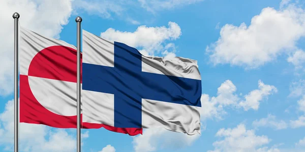 Гренландія і Фінляндія прапор розмахував вітром проти білого хмарного синього неба разом. Концепція дипломатії, міжнародні відносини. — стокове фото