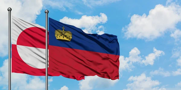 Drapeau du Groenland et du Liechtenstein agitant dans le vent contre le ciel bleu nuageux blanc ensemble. Concept de diplomatie, relations internationales . — Photo