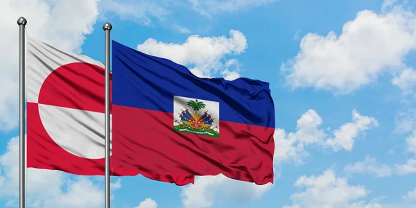 Grönland ve Haiti bayrağı birlikte beyaz bulutlu mavi gökyüzüne karşı rüzgarda sallayarak. Diplomasi kavramı, uluslararası ilişkiler. — Stok fotoğraf