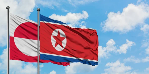 Grönland och Nord Korea sjunker vifta i vinden mot vit grumlig blå himmel tillsammans. Diplomatisk koncept, internationella relationer. — Stockfoto