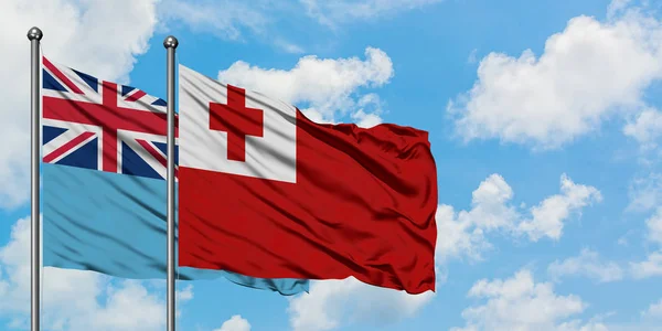 Bandera de Fiji y Tonga ondeando en el viento contra el cielo azul nublado blanco juntos. Concepto diplomático, relaciones internacionales . — Foto de Stock