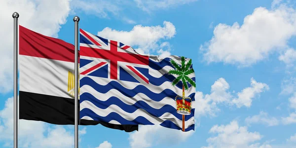 Bandera de Egipto y del Territorio Británico del Océano Índico ondeando en el viento contra el cielo azul nublado blanco juntos. Concepto diplomático, relaciones internacionales . — Foto de Stock