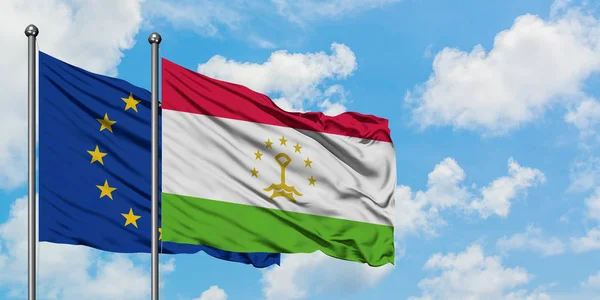 Bandera de la Unión Europea y Tayikistán ondeando en el viento contra el cielo azul nublado blanco juntos. Concepto diplomático, relaciones internacionales . — Foto de Stock