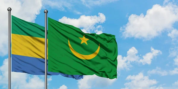 Gabón y Mauritania bandera ondeando en el viento contra blanco cielo azul nublado juntos. Concepto diplomático, relaciones internacionales . — Foto de Stock