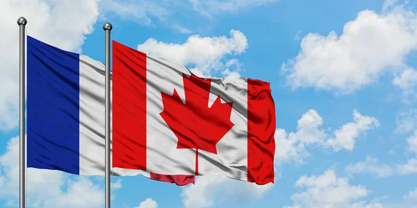 Bandera de Francia y Canadá ondeando en el viento contra el cielo azul nublado blanco juntos. Concepto diplomático, relaciones internacionales . — Foto de Stock