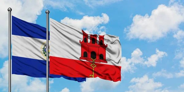 Сальвадор і Гібралтар прапор розмахуючи в вітру проти білого хмарного синього неба разом. Концепція дипломатії, міжнародні відносини. — стокове фото