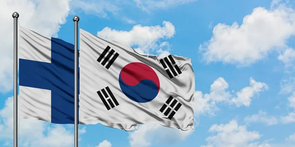 Bandera de Finlandia y Corea del Sur ondeando en el viento contra el cielo azul nublado blanco juntos. Concepto diplomático, relaciones internacionales . —  Fotos de Stock
