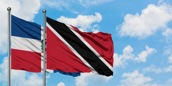 Dominik Cumhuriyeti ve Trinidad ve Tobago bayrağı birlikte beyaz bulutlu mavi gökyüzüne karşı rüzgarda sallayarak. Diplomasi kavramı, uluslararası ilişkiler. — Stok fotoğraf