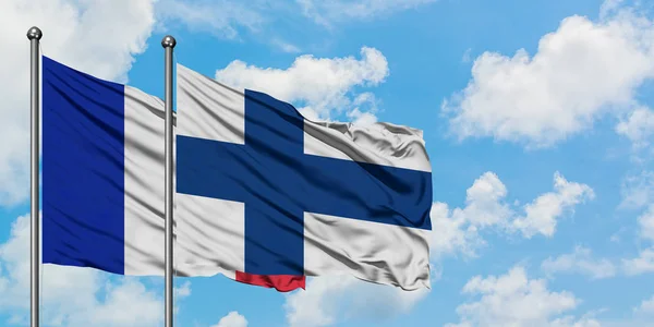 Bandera de Francia y Finlandia ondeando en el viento contra el cielo azul nublado blanco juntos. Concepto diplomático, relaciones internacionales . — Foto de Stock