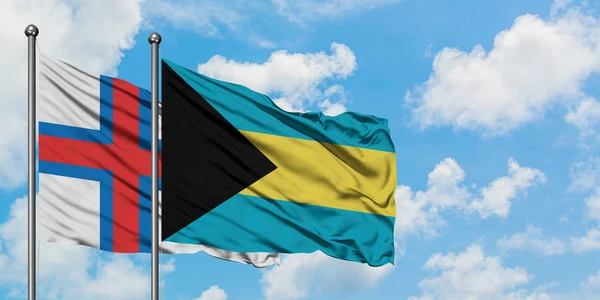 法罗群岛和巴哈马国旗在风中飘扬，与白云相间的蓝天相一起。外交概念、国际关系. — 图库照片