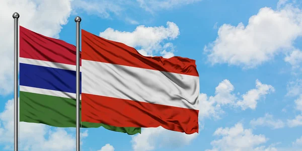 Bandera de Gambia y Austria ondeando en el viento contra el cielo azul nublado blanco juntos. Concepto diplomático, relaciones internacionales . — Foto de Stock