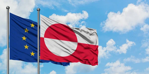 Vlajkou Evropské unie a Grónska mávajících větrem proti bíle zatažené modré obloze. Diplomacie, mezinárodní vztahy. — Stock fotografie