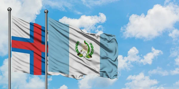 Färöarna och Guatemala sjunker vifta i vinden mot vit grumlig blå himmel tillsammans. Diplomatisk koncept, internationella relationer. — Stockfoto