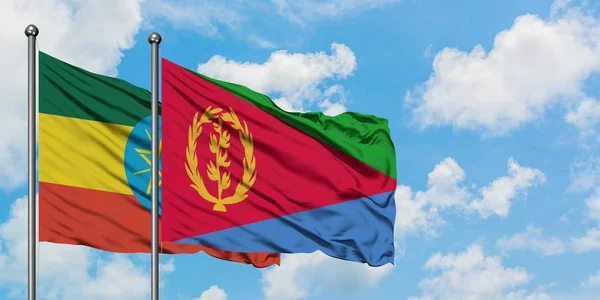 Etiopía y la bandera de Eritrea ondeando en el viento contra el cielo azul nublado blanco juntos. Concepto diplomático, relaciones internacionales . — Foto de Stock