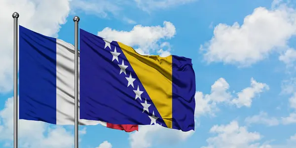 Γαλλία και Βοσνία Ερζεγοβίνη σημαία που κουνώντας τον άνεμο εναντίον του λευκού νεφελώδες γαλάζιο του ουρανού μαζί. Φιλοσοφία της διπλωματίας, διεθνείς σχέσεις. — Φωτογραφία Αρχείου