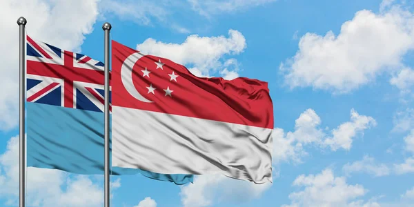 Fiji und Singapore-Flagge wehen gemeinsam im Wind vor weißem wolkenlosem blauen Himmel. Diplomatie-Konzept, internationale Beziehungen. — Stockfoto