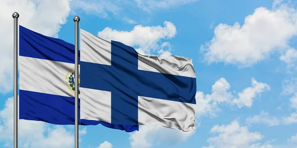 Bandera de El Salvador y Finlandia ondeando en el viento contra el cielo azul nublado blanco juntos. Concepto diplomático, relaciones internacionales . — Foto de Stock
