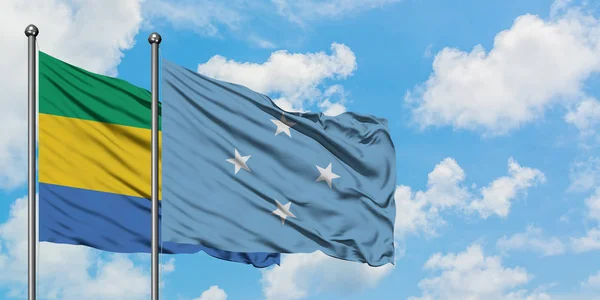 Gabon i Mikronezja flaga machając w wiatr przed białym zachmurzone błękitne niebo razem. Koncepcja dyplomacji, stosunki międzynarodowe. — Zdjęcie stockowe