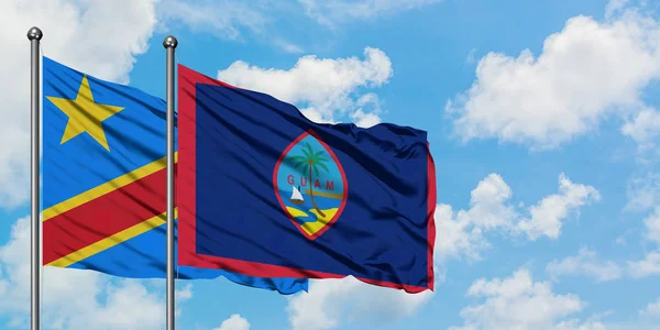 Bandera del Congo y Guam ondeando en el viento contra el cielo azul nublado blanco juntos. Concepto diplomático, relaciones internacionales . — Foto de Stock