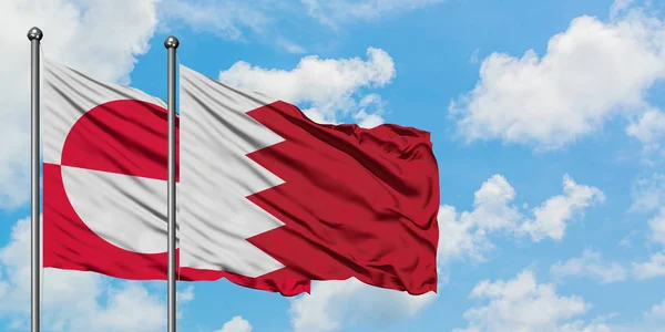 Bandera de Groenlandia y Bahréin ondeando en el viento contra el cielo azul nublado blanco juntos. Concepto diplomático, relaciones internacionales . — Foto de Stock